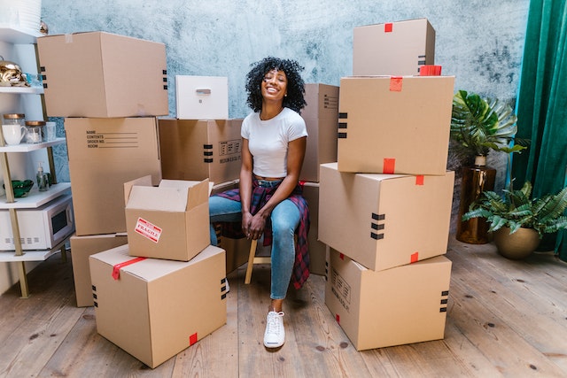 someone sitting on a stool surrounded by moving boxes